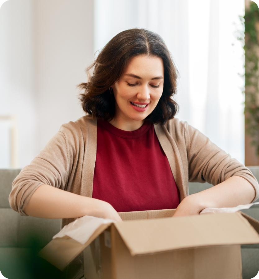 Smiling woman opening a cardboard delivery box at home