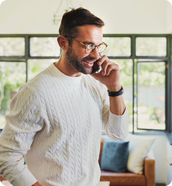 Smiling man in glasses taking a phone call at home