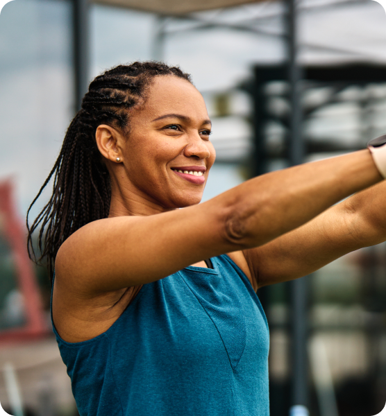 Smiling woman with braided hair exercising outdoors in a blue vest top